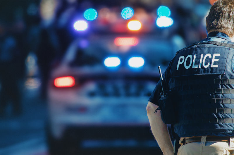 The back of a policeman with a police car blurred in the background