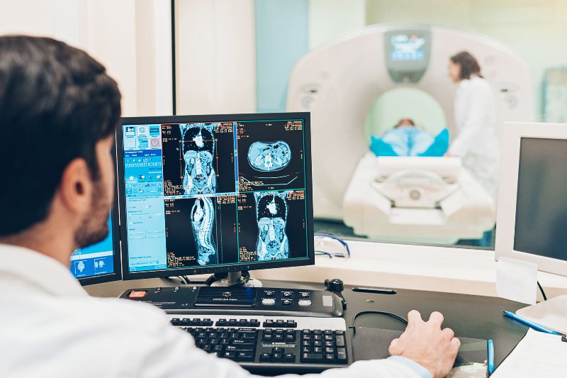 A medical professional looking a screen displaying scan images