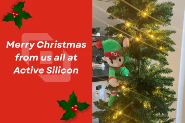 An elf in a Christmas tree with a festive message