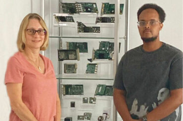 Two people standing in front of cabinet of computer imaging products