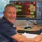 An engineer sitting at a computer with PCB design on the screen