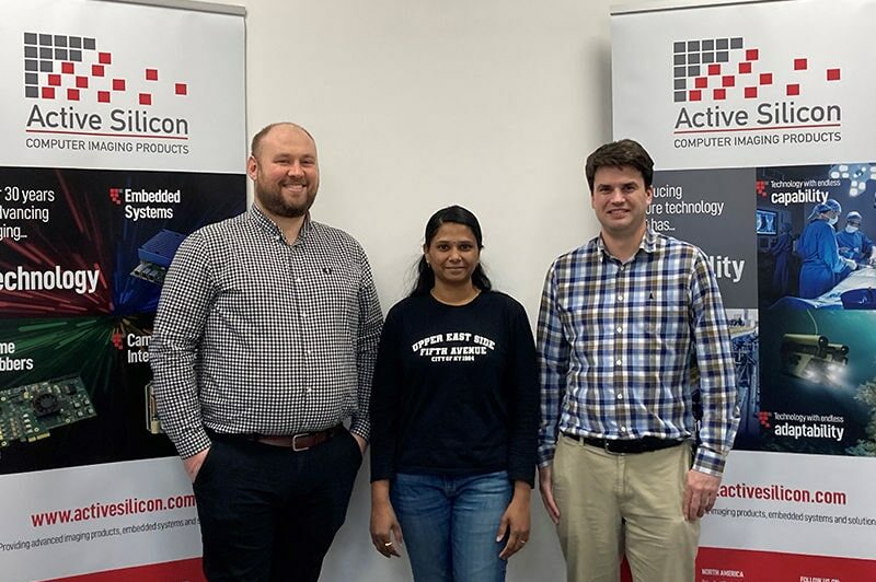 Active Silicon’s newest team members standing in front of corporate banners