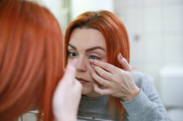 Lady looking in a mirror while inserting a contact lens
