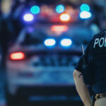 The back of a police officer standing in front of a police car