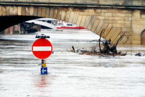 A street sign just visible above deep flood waters on a road